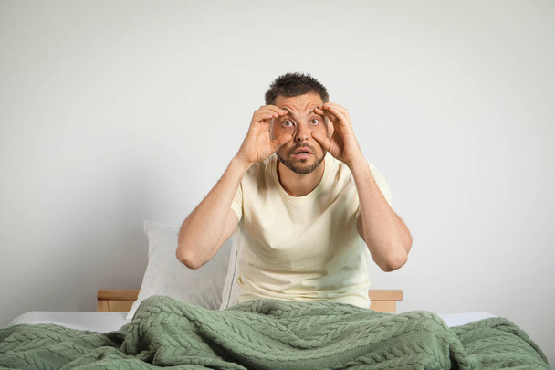 Sleepless man sitting on bed at home - Photo, Image