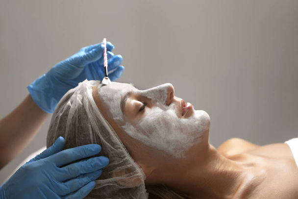 Cosmetologist applying mask on client's face in spa salon - Fotoğraf, Görsel