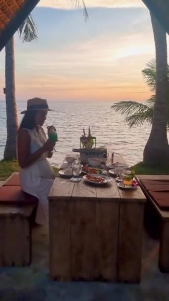 Gün batımında Tayland yemekleriyle kumsalda romantik bir akşam yemeği, gün batımında Asyalı Taylandlı kadınlar akşamları Koh Mak Tayland adasında akşam yemeği. - Video, Çekim