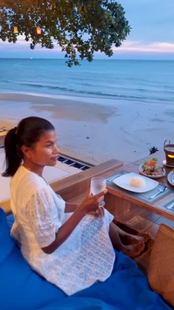 Gün batımında Tayland yemeğiyle sahilde romantik bir akşam yemeği, gün batımında Asyalı Taylandlı kadınlar akşam yemeği. - Video, Çekim