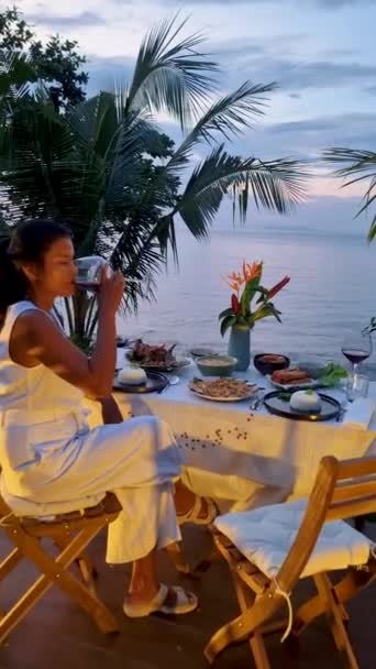 Cena romantica sulla spiaggia con cibo thailandese durante il tramonto, donne asiatiche thailandesi durante il tramonto cena sulla spiaggia di Koh Kood Thailandia la sera - Filmati, video