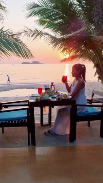Cena romántica en la playa con comida tailandesa al atardecer, mujeres tailandesas asiáticas al atardecer cenando en la playa de Koh Chang Tailandia - Imágenes, Vídeo