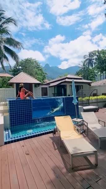 Paar ontspannen voor hun zwembad villa tijdens een luxe vakantie. Mannen en vrouwen in een luxe zwembad - Video
