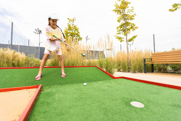 Красива маленька дівчинка грає в міні-гольф
. - Фото, зображення