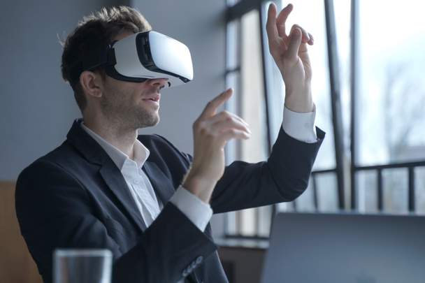 Cyberspace in business. Excited man office worker wearing vr goggles touching objects with hands in digital world, amazed businessman in 3d glasses interacting with virtual reality at work - Foto, Imagen