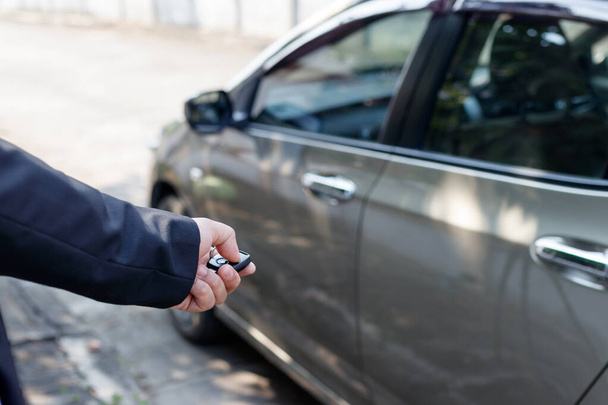Business man holding car keys with car on background. - Фото, зображення