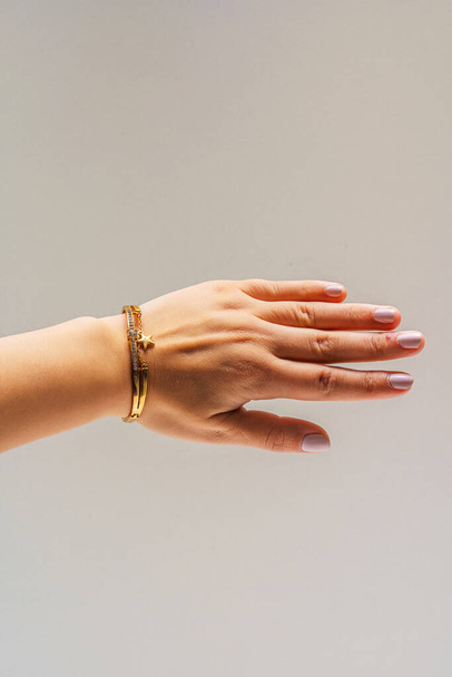Beyaz arka planda altın bileziği olan bir kadın eli. Üzerinde yaldızlı mücevherler olan bir kız. Katalog için bojouterie fotoğrafları - Fotoğraf, Görsel