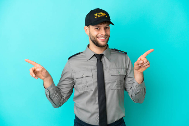 Young security man isolated on blue background pointing finger to the laterals and happy - Photo, Image
