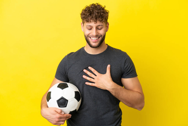 Komea nuori jalkapalloilija mies eristetty keltaisella taustalla hymyillen paljon - Valokuva, kuva