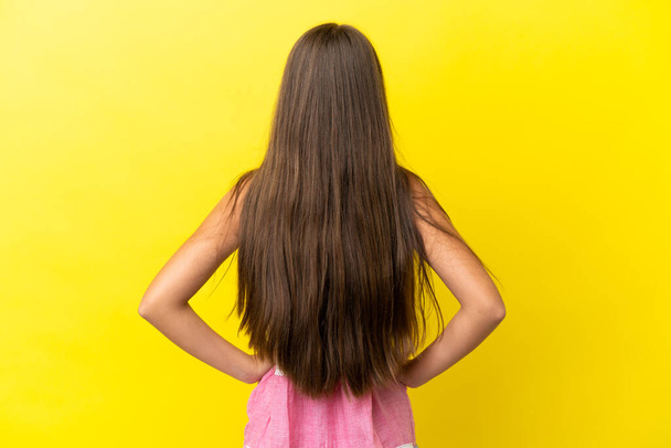 Little caucasian girl isolated on yellow background in back position - Foto, Bild