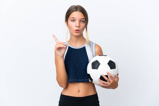 Маленькая кавказская девочка, играющая в футбол на белом фоне, намеревается найти решение, поднимая палец. - Фото, изображение