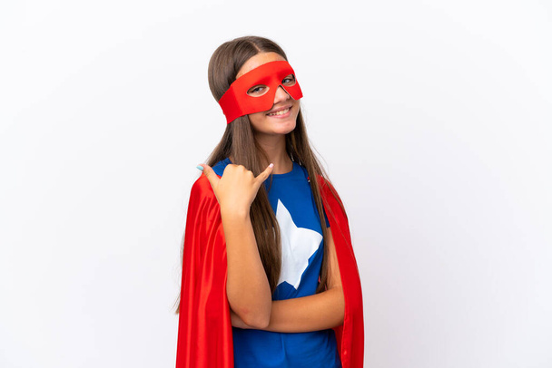 Little caucasian girl isolated on white background in superhero costume and doing phone gesture - Фото, зображення