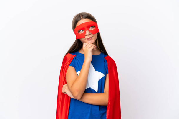 Little caucasian girl isolated on white background in superhero costume and thinking - Photo, image