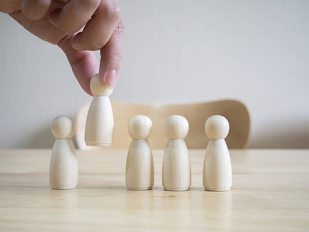 Hands of businesswoman choose wooden figure. The concept of choosing leaders for business success. Organization development. Leadership. Personnel selection. Wooden puppet. Wooden peg dolls. - Photo, Image