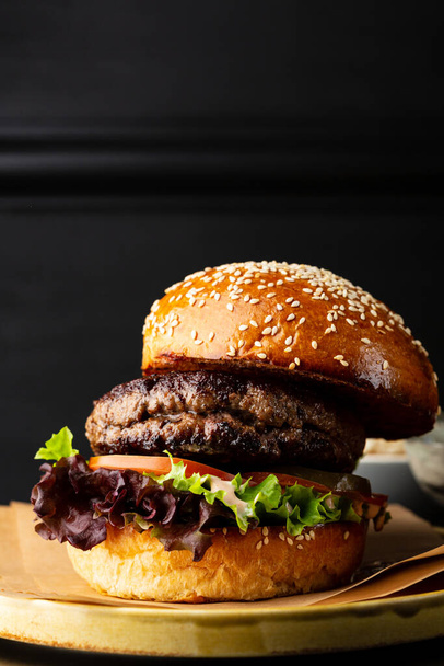 Close up of tasty cheeseburger on dark table copy space food - Fotó, kép