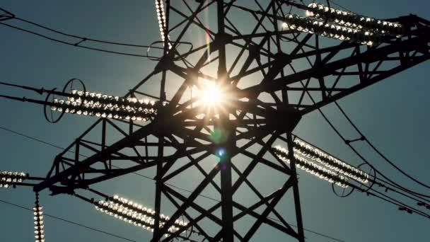 Power lines with sun rays on blue sky. High voltage substation. Electricity crisis in the world. Green energy in power lines. Selective soft focus - Footage, Video