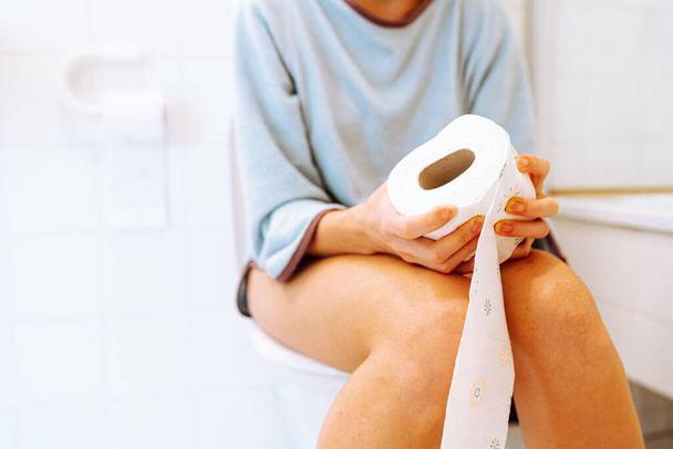 Silhouette einer Frau, die auf Toilette auf verschwommenem Hintergrund sitzt. Kranke, ungesunde Frau, Teenager, die an Durchfall, Verstopfung und Blasenentzündung in der Toilette leiden. Bauchschmerzen bei PMS. Gesundheits- und Schmerzkonzept - Foto, Bild