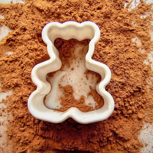 cacao en polvo y moldes para hornear en forma de oso sobre un fondo claro - Foto, imagen