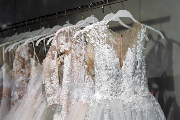 Beautiful bridal dress on hangers. Wedding dress close up at the wedding salon. Wedding dresses hanging on a hanger. Interior of bridal salon. - Photo, Image