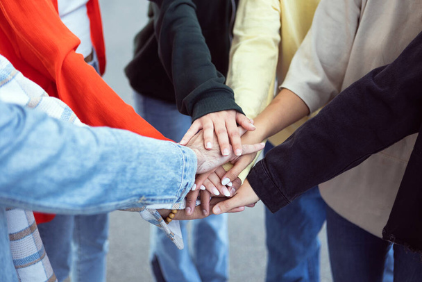 Wielorasowa młodzież łącząca dłonie na świeżym powietrzu - koncepcja jedności i wspólnoty z różnorodną grupą milenijnych przyjaciół łączących dłonie - Zdjęcie, obraz