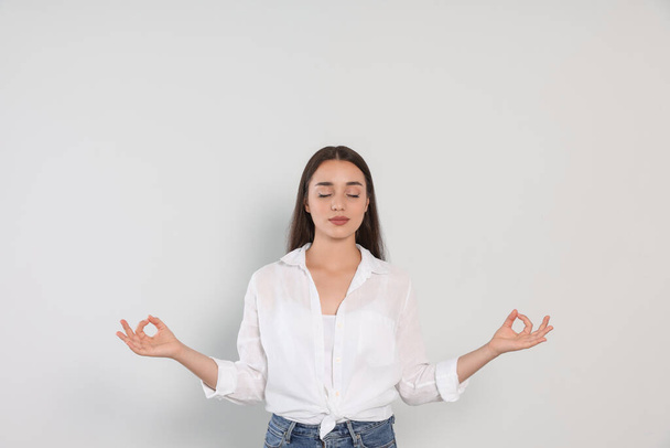 Find zen. Beautiful young woman meditating on white background - Fotoğraf, Görsel