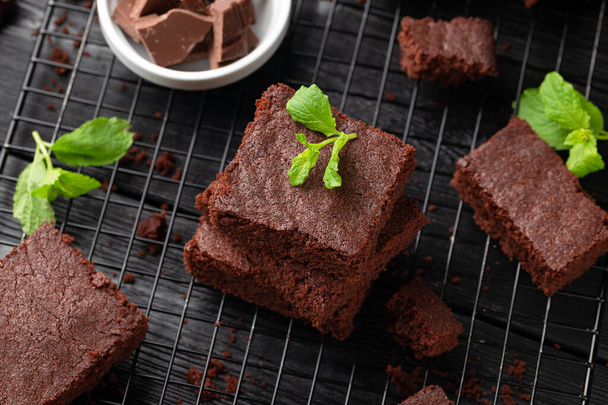 Chocolate brownies garnished with mint on cooling rack. Sweet food. - Photo, Image