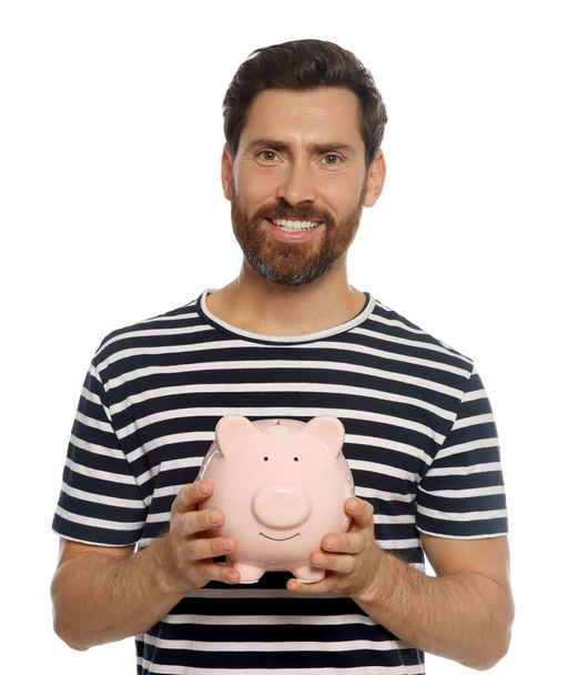 Happy man with ceramic piggy bank on white background - Photo, Image