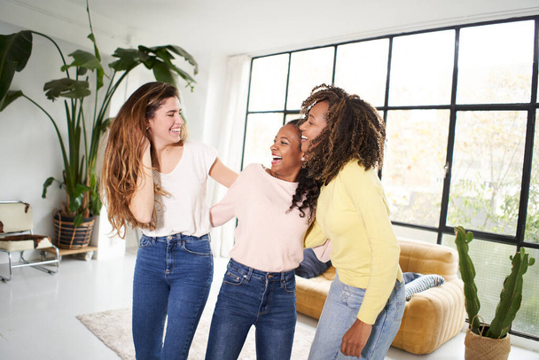 Trzy śmieszne przyjaciółki tańczące i śpiewające na kanapie w domu. Wielorasowe szczęśliwe kobiety grać i świętować radość życia Wesołe dziewczyny cieszyć się razem w domu zabawy. - Tak. Wysokiej jakości zdjęcie - Zdjęcie, obraz