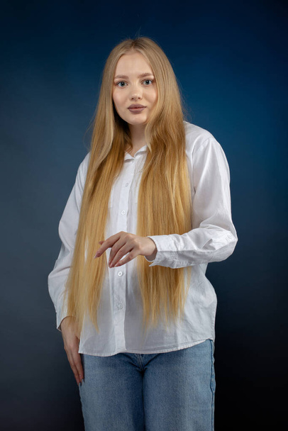 ブロンド女の子でジーンズと白いシャツ上の青の背景 - 写真・画像