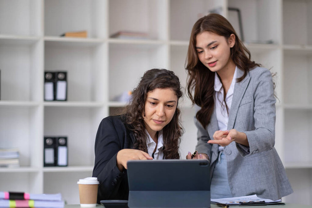 Two young Asian business woman talk, consult, discuss working with new startup project idea presentation analyze plan marketing and investment in the office.. - Foto, Imagen