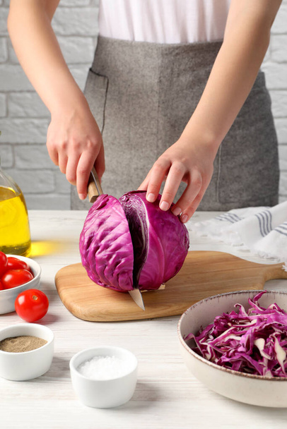 Woman cutting fresh red cabbage at white wooden table, closeup - Fotó, kép
