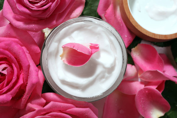 Jar of face cream among beautiful roses, top view - Fotoğraf, Görsel