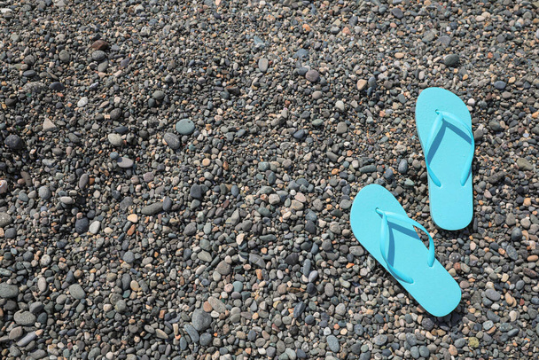 ビュー上の小石のビーチでスタイリッシュなターコイズブルーのフリップループ。テキストのスペース - 写真・画像