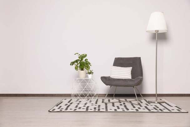 Stylish armchair, floor lamp and plants near white wall. Space for text - Foto, immagini