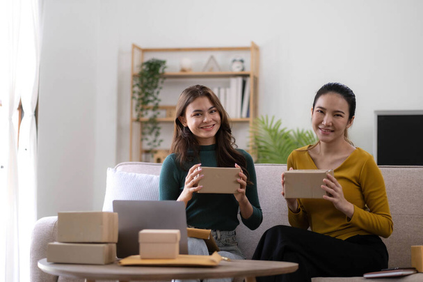 Portrait of Starting small businesses SME owners, two Asian woman check online orders Selling products working with boxs freelance work at home office, sme business online small medium enterprise. - Photo, Image