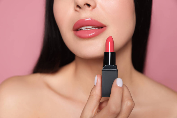 Young woman with beautiful makeup holding glossy lipstick on pink background, closeup - Valokuva, kuva