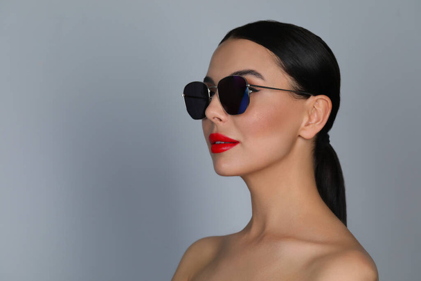 Attractive woman in fashionable sunglasses against grey background. Space for text - Fotoğraf, Görsel