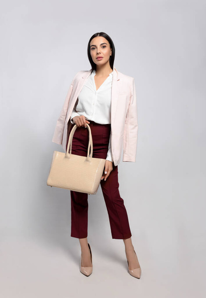 Young woman with stylish bag on white background - Foto, afbeelding