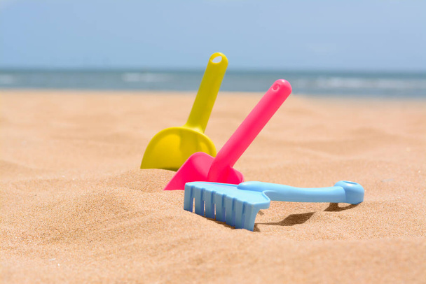 Set of colorful beach toys on sand near sea - Foto, Bild