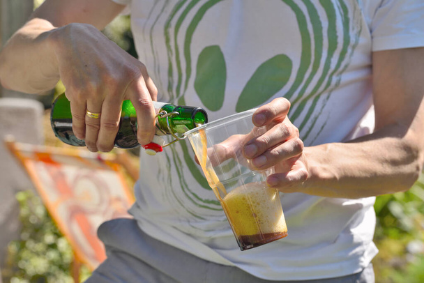 Man pouring a glass of beer in the garden - Photo, Image