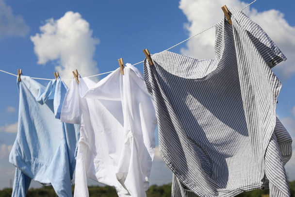 Clean clothes hanging on washing line against sky. Drying laundry - Fotoğraf, Görsel