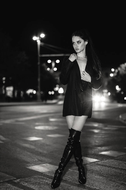 fashion outdoor photo of beautiful woman with dark hair in elegant outfit walking by the night city - Фото, изображение