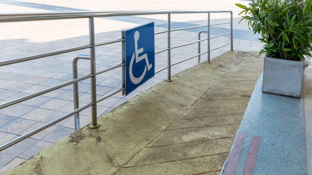 Disabled way sign in front of building. Handicapped sign traffic symbol on the floor in front of ramp way for support wheelchair. Disabled way sign in front of cafe on green nature landscape. - Foto, immagini