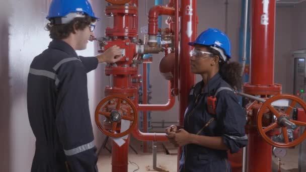 Young woman and man engineer check and examining pipeline and discussion in the factory, mechanic or technician inspector plumber valve and talking together, industrial and maintenance concept. - Metraje, vídeo