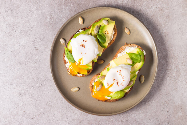 Toast with avocado, soft cream cheese, rye bread and poached Egg. Wholemeal open sandwich for healthy breakfast concept. - Φωτογραφία, εικόνα
