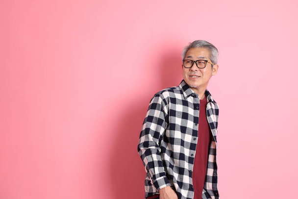 Los años 40 adulto asiático hombre stnading en el rosa fondo con casual ropa. - Foto, Imagen