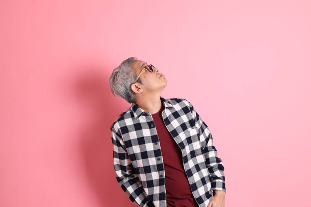 A 40-es évek felnőtt ázsiai férfi stnading a rózsaszín háttér alkalmi ruhák. - Fotó, kép