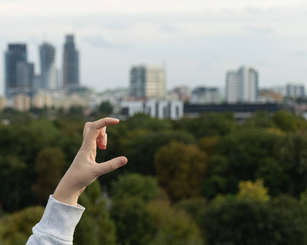Порожня рука з розмитим панорамним видом на місто. Порожній вид збоку долоні, руки, що тримають щось
 - Фото, зображення