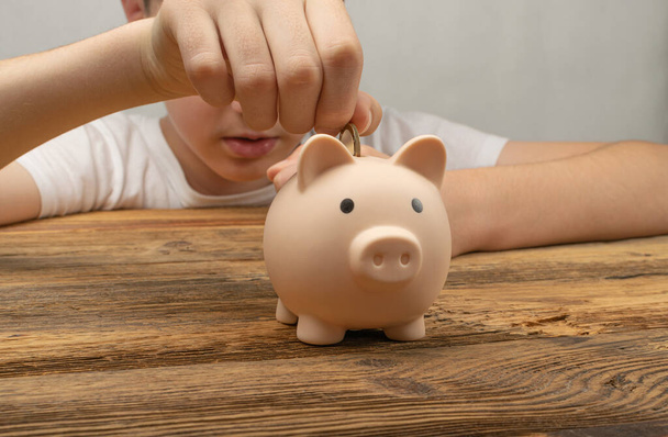 Child Throws Coin into piggy bank. Money box, saving pig, small moneybox, planning home finances concept, piggybank, piggy bank - Zdjęcie, obraz