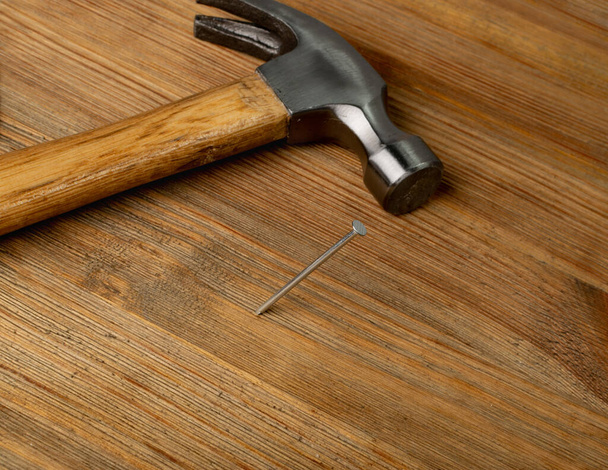 Metal nail and hammer on wooden desk. Steel nails on wood plate, construction hardware on brown wood background - Foto, Imagem